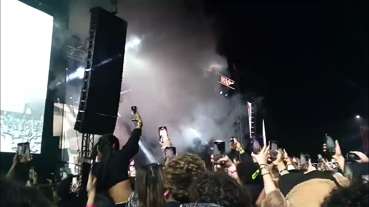 A packed concert crowd under red stage lights